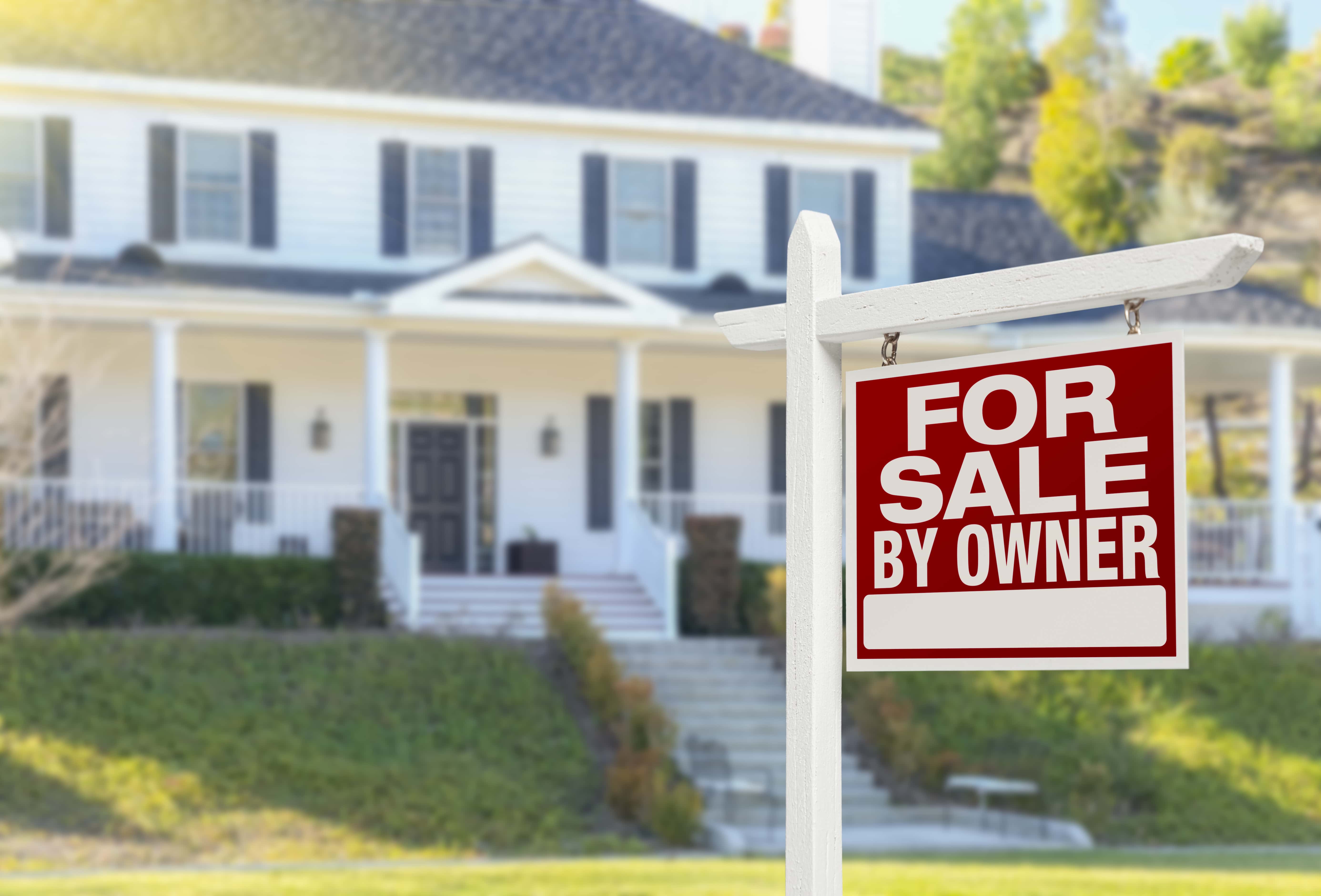 For sale by owner sign in front of a house