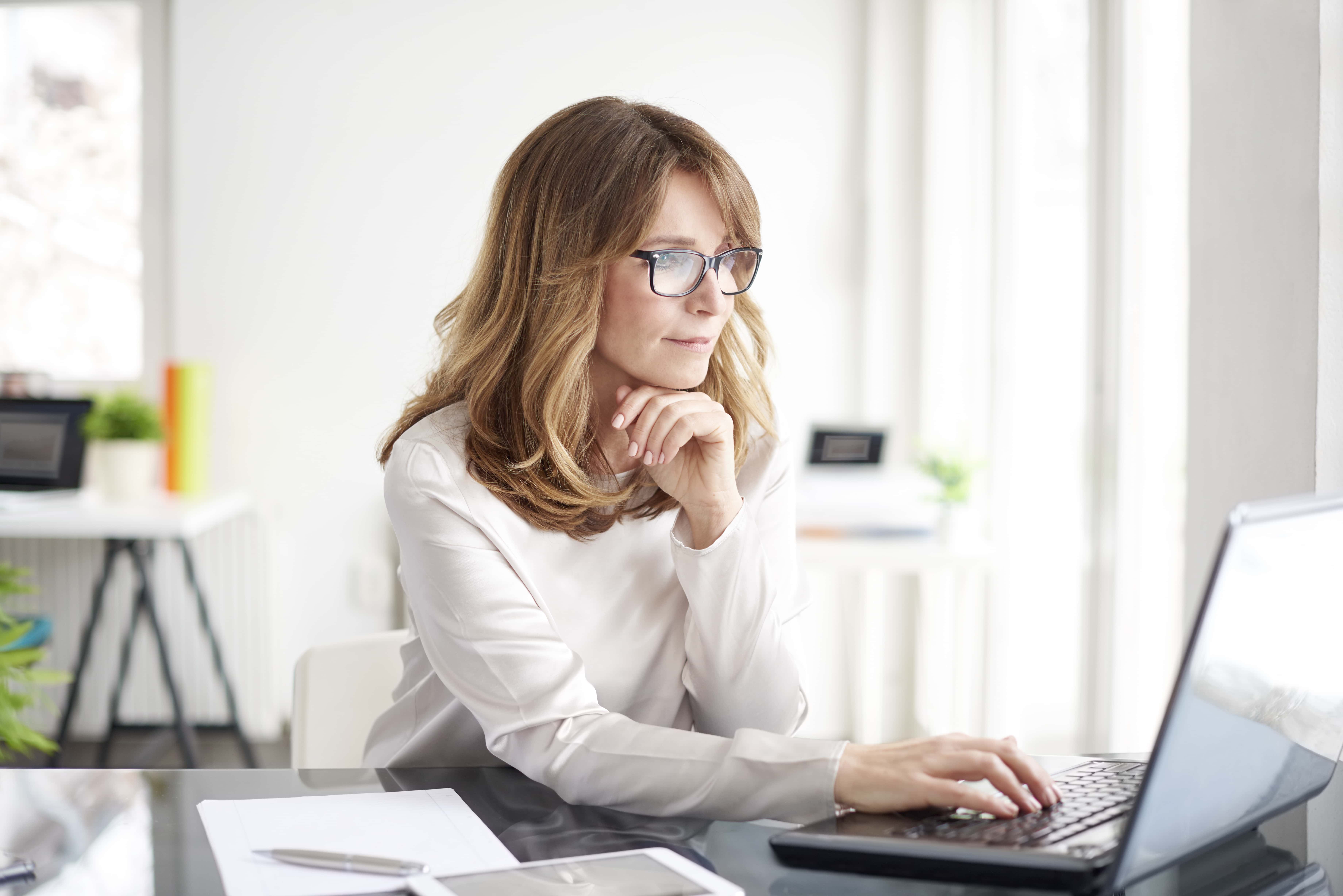 Woman on computer with notes by her side